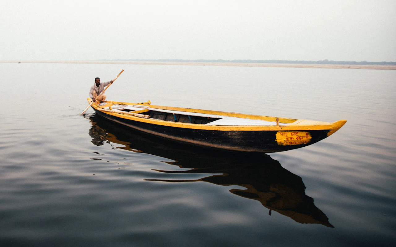 A boatman rowing a wooden boat on the Ganga at Varanasi