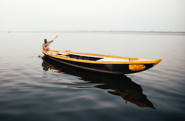 A boatman rowing a wooden boat on the Ganga at Varanasi